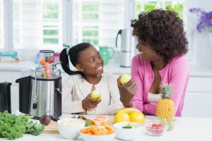 African American mother and daughter in kitchen making healthy breakfast