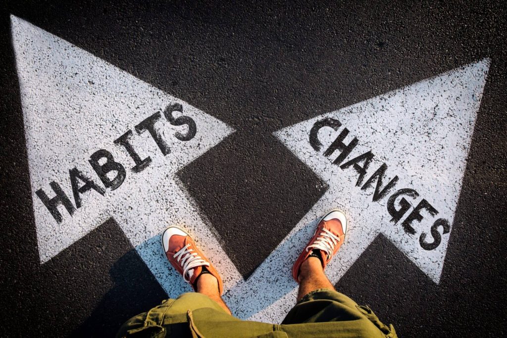 Two arrows in road, one that says habits and the other says changes