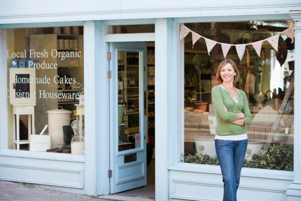 Woman business owner smiling in front of her store