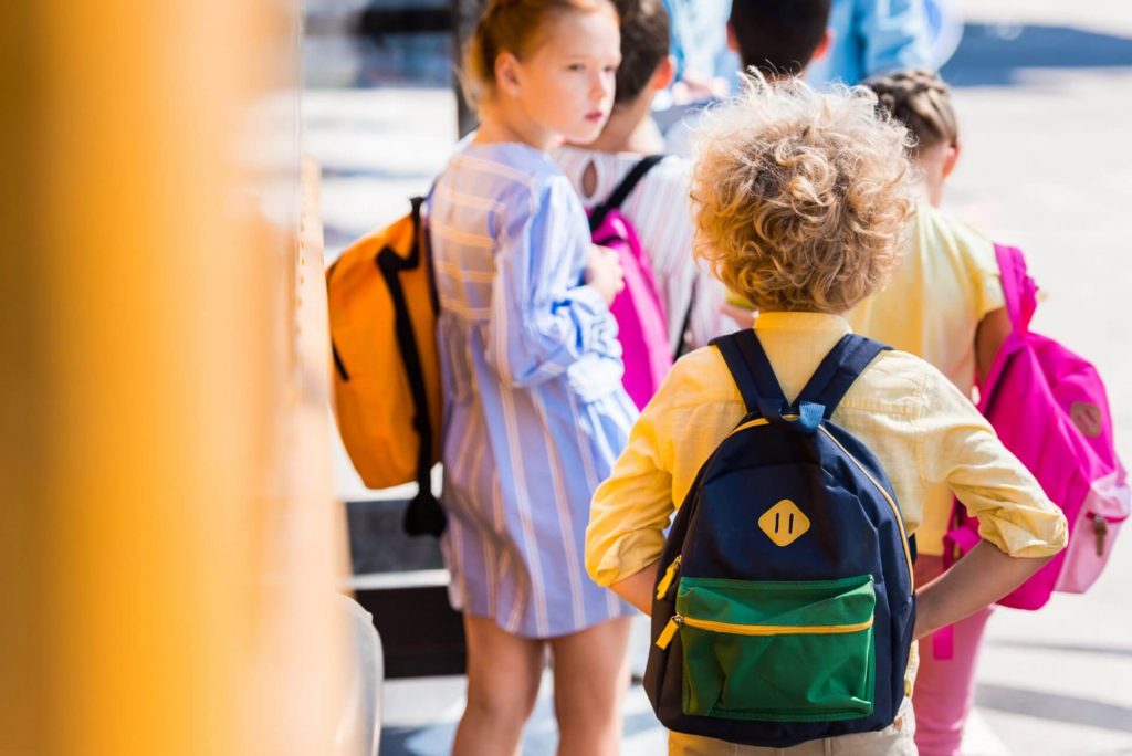 Young children with backpacks getting on school bus